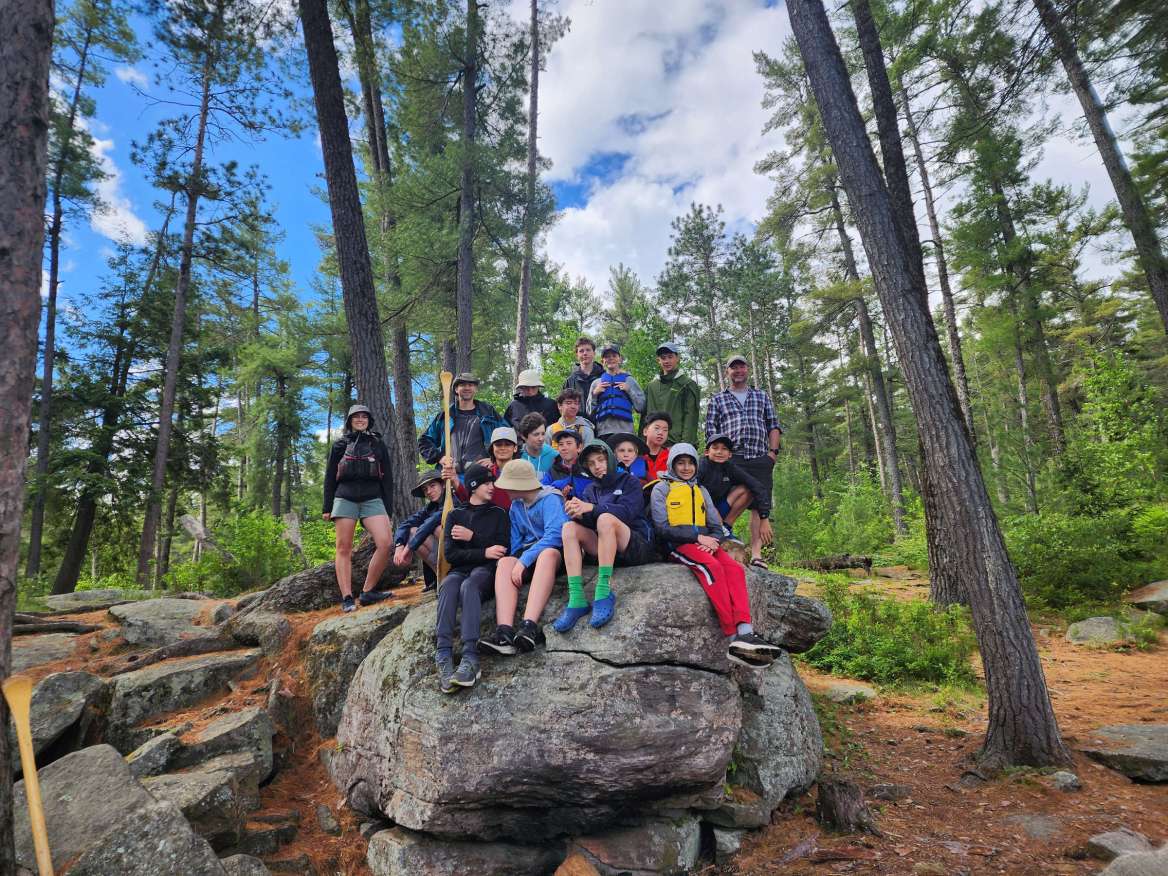 The 3rd Ottawa Scout Troop resting on a rock during a hike in nature.